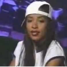 a woman with long hair wearing a white hat and holding a microphone in front of her face