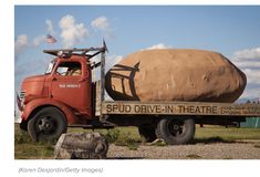 an old red truck with a large rock in the back