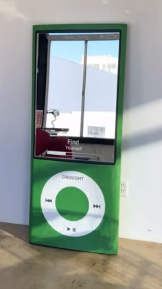 an ipod sitting on top of a wooden table next to a wall with a window