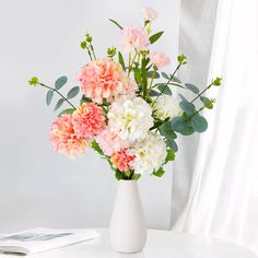 a white vase filled with pink and white flowers