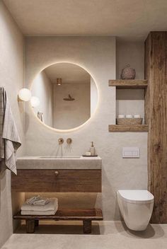 a white toilet sitting next to a wooden shelf in a bathroom under a round mirror