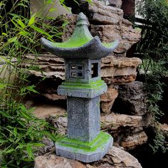 a stone pagoda sitting on top of a pile of rocks next to a planter