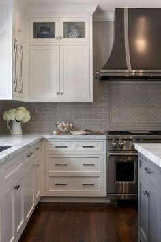 a large kitchen with white cabinets and stainless steel range hoods over the stove top