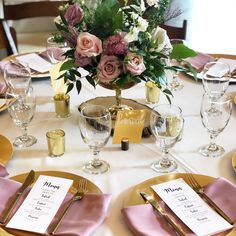 the table is set with pink napkins and gold place settings