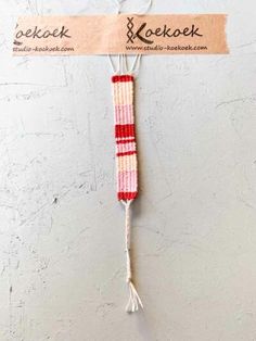 a red and white piece of cloth hanging on a wall with a tag attached to it