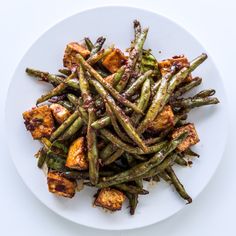 a white plate topped with green beans and tofu