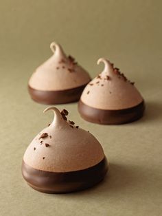 three chocolate covered desserts sitting on top of a table