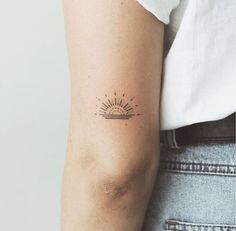 a woman's arm with a small sun tattoo on the left side of her arm