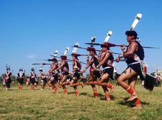 a group of people that are standing in the grass with some swords on their heads