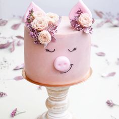 a pink cake decorated with flowers and a pig's face on top of it