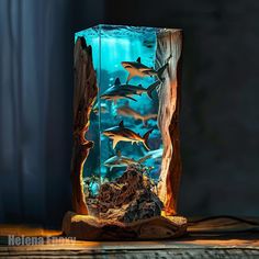 an aquarium filled with sharks and other marine creatures is displayed on a wooden table in front of a window