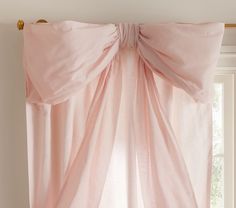 a pink curtain hanging on the side of a window