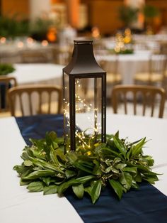 a lantern on top of a table with greenery