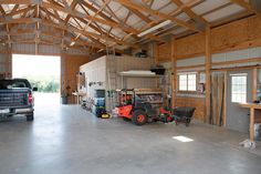 a truck parked in a garage next to a large building with wood framing on the walls