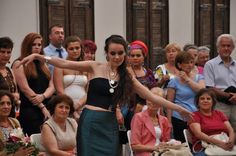 a woman standing in front of a crowd with her arms out and one arm extended