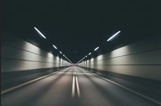 an empty tunnel with light at the end and no cars on it in the distance