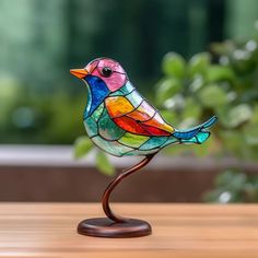 a colorful glass bird sitting on top of a wooden table