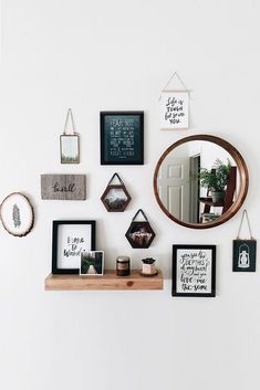 a white wall with various frames and pictures on the wall, including a round mirror