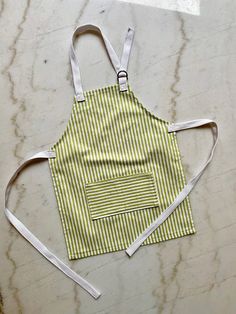 an apron with straps on it sitting on top of a marble counter next to a pair of scissors