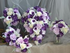 purple and white bridal bouquets sitting on a table