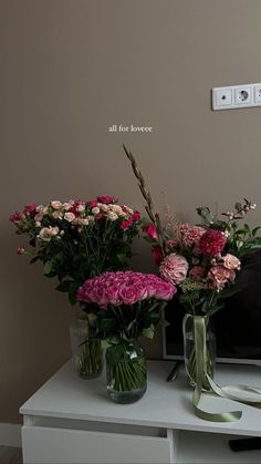 two vases filled with flowers sitting on top of a table next to a tv