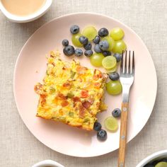 a white plate topped with food next to two bowls of grapes and a cup of coffee