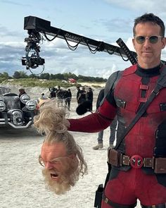 a man in a deadpool suit is being filmed by a woman with blonde hair