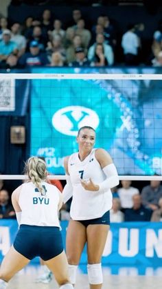 two women playing volleyball in front of an audience