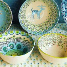 three bowls with designs on them sitting on a tablecloth covered surface, one has a deer and the other is peacock