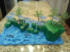 a cake made to look like an island with palm trees and dolphins in the water