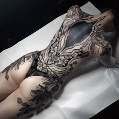 a woman laying on top of a bed covered in tattoos