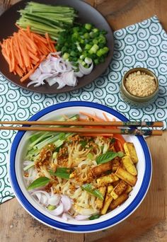 a bowl filled with vegetables and chopsticks next to another bowl full of food