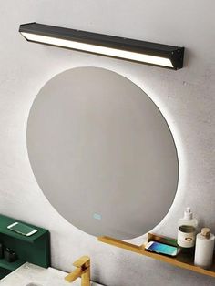 a bathroom mirror with lights above it and a shelf on the wall next to it