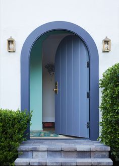 a blue door is open on a white building with steps leading up to the entrance