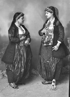 two women standing next to each other in front of a wall