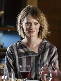 a woman sitting at a table with wine glasses