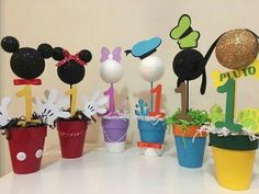 there are many mickey mouse cupcake toppers in the potted planters on the table