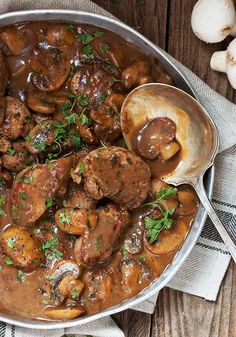 meat and mushroom stew in a pan with spoon