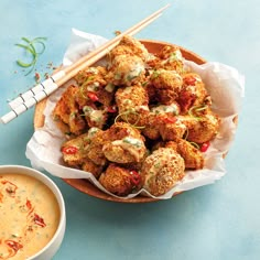 a bowl filled with fried food next to a bowl of dipping sauce