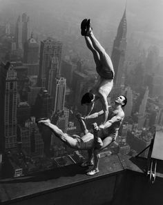 two men doing acrobatic tricks on top of a building in new york city