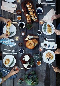 several people are eating food on a wooden table