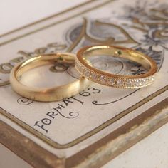 two gold wedding rings sitting on top of a table