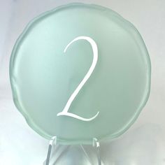 a glass plate with the number two on it sitting on a metal stand in front of a white background