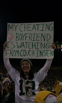 a woman holding up a sign that says, my cheering boyfriend is watching from couch instead