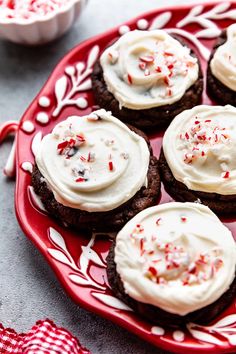 chocolate cookies with white frosting and sprinkles on a red plate