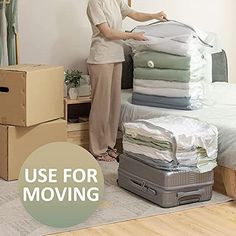 a woman standing next to a pile of luggage in a room with cardboard boxes on the floor