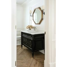 a black and white bathroom vanity with mirror, sink and flowers on the counter top