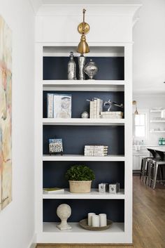 a white book shelf with books and plants on it