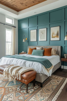 a bedroom with teal walls and white bedding, wooden flooring, an ottoman on top of the bed