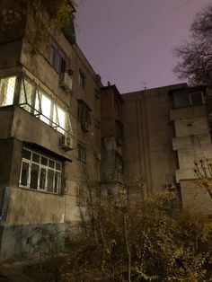 an old building is lit up at night with the moon in the sky behind it